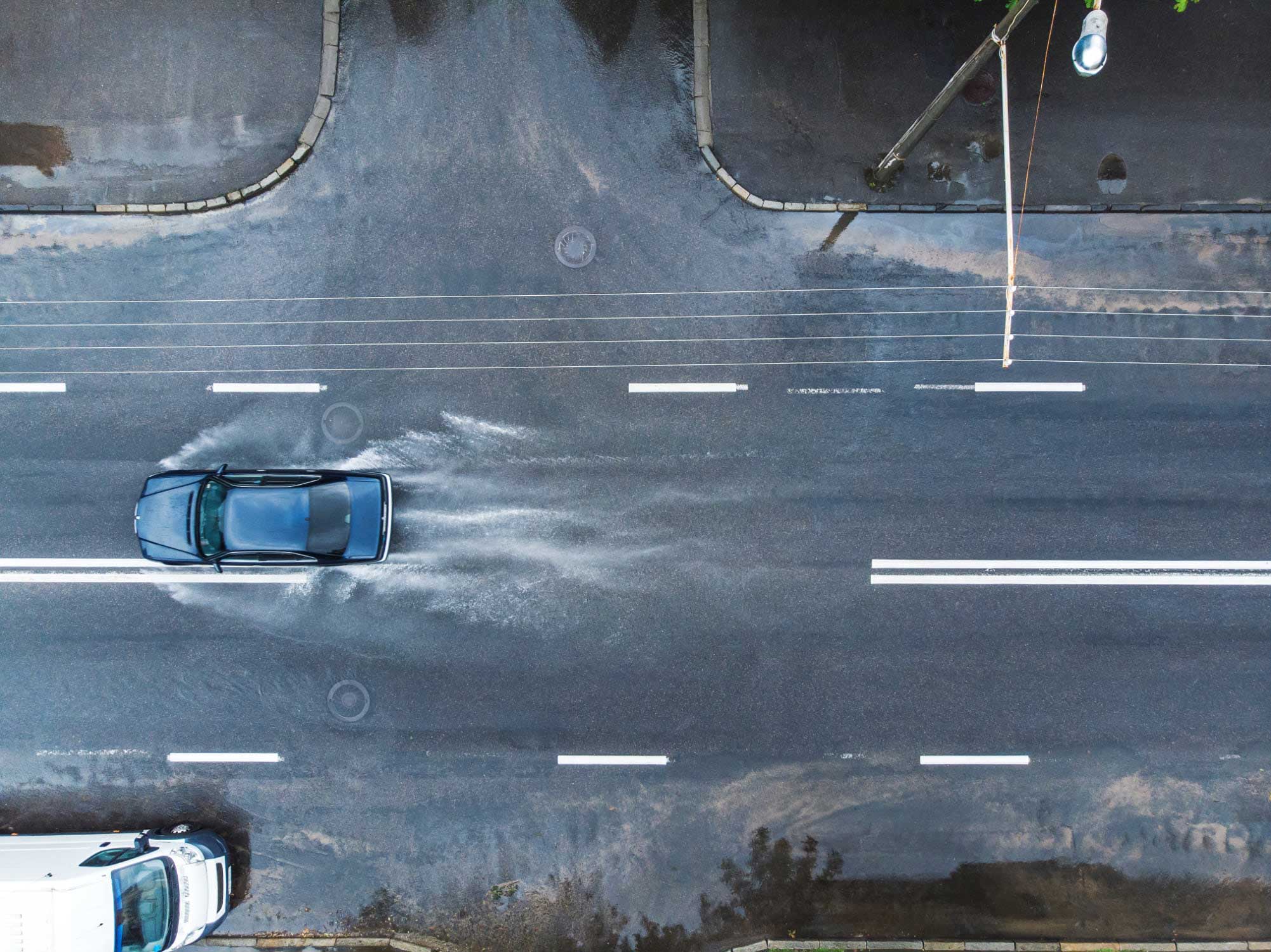 Aerial photo pf car driving on rain-soaked street